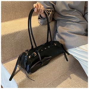 Detail view of black vintage oil wax leather baguette bag with golden buckle on stairs