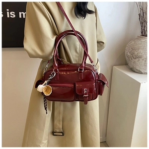 Detail view of burgundy shiny leather handbag with multiple pockets and shoulder strap
