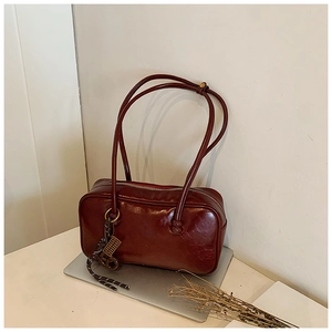Détail du sac à main rétro en cuir ciré rouge foncé avec pendentif boulier unique