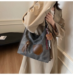 Detail of grey hobo tote bag with soft PU leather texture and plush bear charm on strap