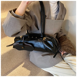 Detail of black glossy oil wax leather baguette bag with dual straps and mini pouch