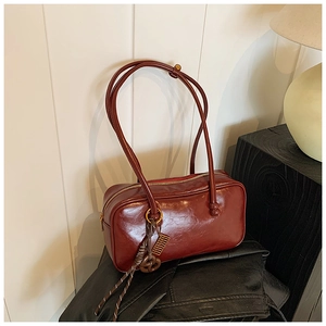 Détail du sac Boston en cuir ciré brillant bordeaux avec breloque décorative