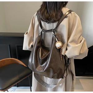 Dettaglio della borsa tote vintage in pelle marrone con ciondolo da baseball e zip rifinita
