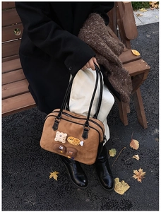 Detail of vintage brown suede tote bag with cartoon 3D charms and black leather straps