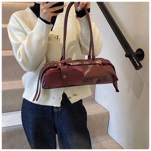 Close-up of dark red oil wax leather baguette bag with vintage hardware details