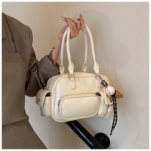 Detail of cream bowling bag with multiple pockets and sports baseball charm accessory
