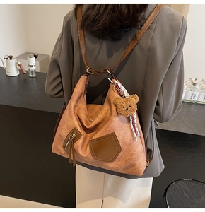 Detail of a brown leather hobo bag featuring litchi texture and decorative scarf