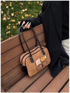 Detail showing vintage suede texture and cute 3D cartoon patches on brown shoulder bag