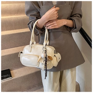 Detailed close-up of cream bowling bag with multiple pockets and baseball-themed charms