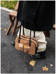 Close-up of brown suede bag with cute food plush charms on an autumn park bench