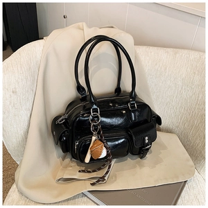 Close-up of a glossy black pleated leather bowling bag with a baseball themed pendant charm