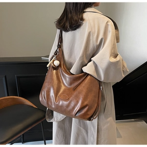Dettaglio della borsa tote marrone scuro vintage con texture cerata e ciondolo a sfera