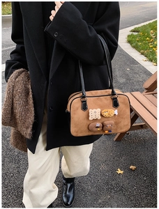 Close-up of vintage brown suede shoulder bag featuring cute cartoon biscuit charms and 3D patches
