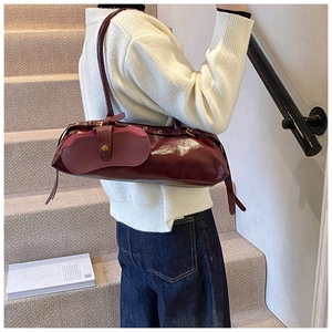 Detailed view of burgundy glossy leather baguette bag with vintage gold clasp on stairs