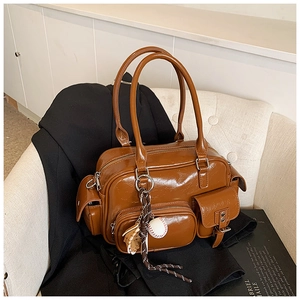 Macro detail of glossy brown PU leather handbag with zipper pocket and sports charm