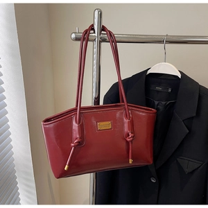 Detail of burgundy oil wax leather tote with knot strap and gold plaque decoration
