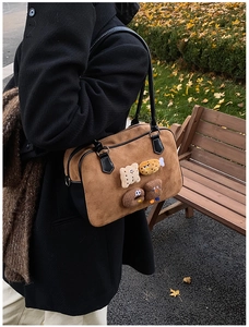 Brown suede shoulder bag with cute cartoon patches on a scenic autumn outdoor background