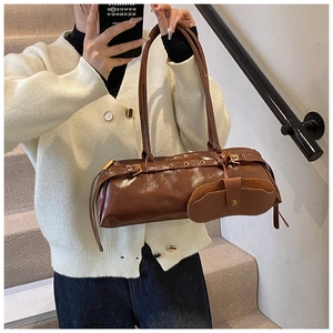 Detail view of retro brown wax leather baguette bag with buckles and round coin pouch