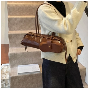 Close-up of retro brown oily leather baguette bag with metal eyelet strap detail