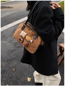 Detail view of brown faux suede pillow bag with cute plush bear and toast charms