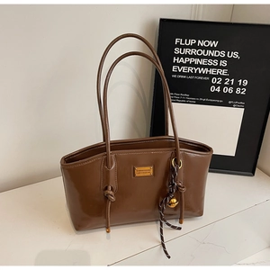 Detail view of dark brown oil-wax leather tote with golden nameplate and knotted handles
