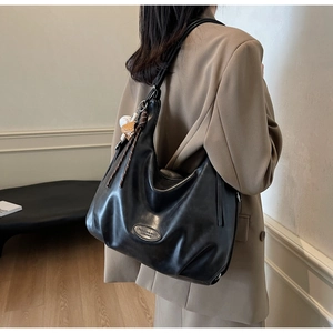 Dettaglio della borsa Hobo in morbida pelle nera con logo metallico e finitura liscia