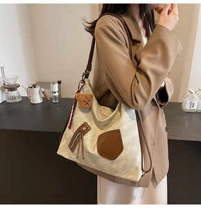 Detail of off-white canvas hobo bag with brown leather straps and striped scarf charm