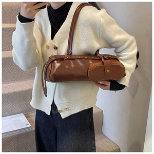 Detailed view of dark brown oil-wax leather texture with gold metal hardware on baguette bag