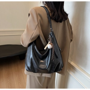 Dettaglio della borsa tote in pelle nera retrò con logo in metallo e ciondolo da baseball