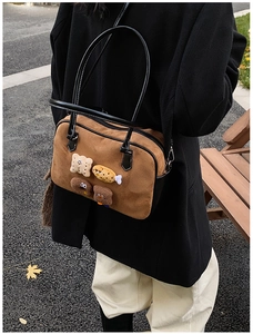 Detail view of brown vintage boston bag with cute cartoon plush patches on outdoor road