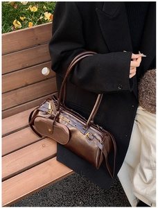 Detail of vintage dark brown faux leather cylinder bag with gold metallic hardware buckles
