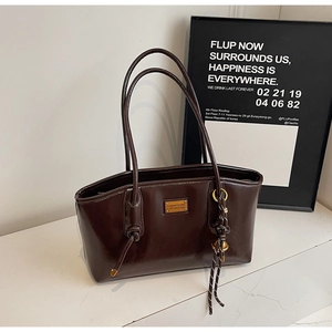 Detail of dark brown oil wax leather tote with gold metal plate and knot strap design