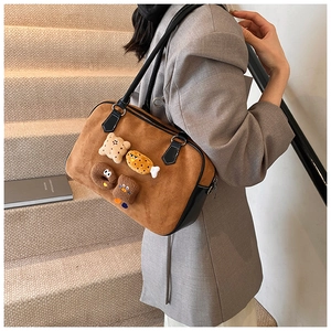 Close-up of brown frosted tote bag featuring creative plush cartoon patches and leather handles