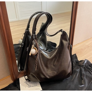 Dettaglio ravvicinato di una borsa tote in pelle marrone vintage con ciondolo baseball