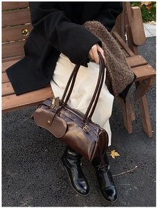 Detail view of vintage brown oiled leather bag with metal eyelets and side pouch