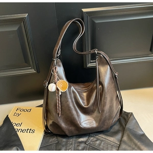 Dettaglio della borsa hobo in pelle marrone con trama vintage e ciondolo guanto da baseball