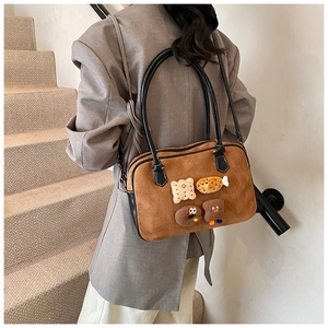 Detail of brown suede tote bag with cartoon food patches held by a model on stairs