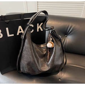 Dettaglio della borsa hobo vintage con trama in pelle e logo su divano nero