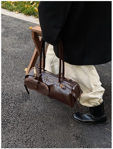 Detail view of a vintage dark brown oil wax leather baguette shoulder bag in outdoor setting