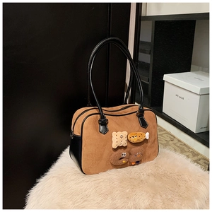 Close-up of brown suede bag with cute cartoon embroidery and black leather straps