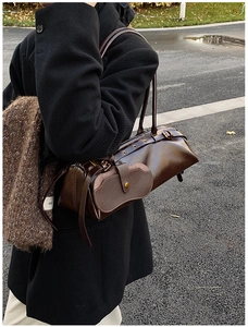 Detail of dark brown polished leather shoulder bag with vintage strap and small side pouch