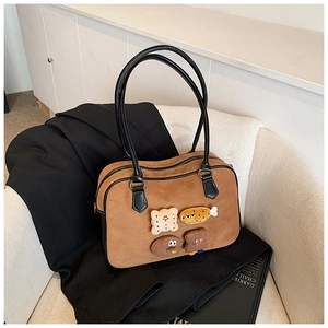 Detail of brown suede pillow bag with cute cartoon plush patches on a textured sofa