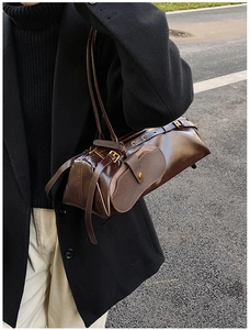 Close-up of dark brown oil wax leather bag with decorative straps and bronze hardware