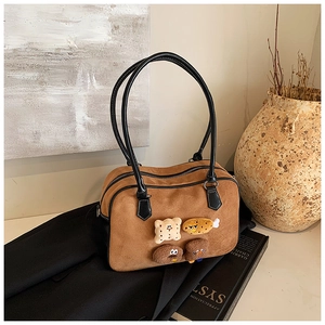 Detail of brown suede shoulder bag with cute plush patches in a home setting