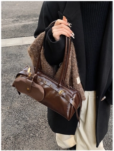 Detail view of deep brown vintage baguette bag with metallic buckles in a street style setting