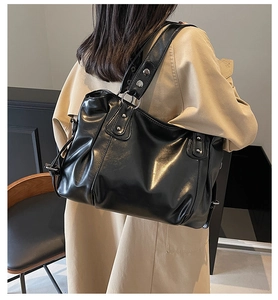 Détail d'un grand sac cabas noir en similicuir brillant avec des rivets argentés chic