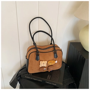 Detailed view of brown suede pillow bag with cute cartoon patches and black leather handles