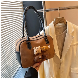Detail view of brown suede pillow bag with cute plush cookie and donut patches