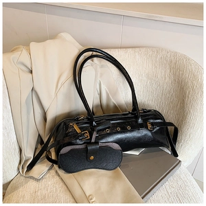 Detail of black glossy cylindrical bag with metallic eyelets and detachable mini pouch
