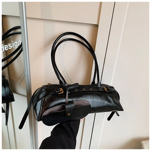 Detail of black glossy leather shoulder bag with gold buckles and small pouch